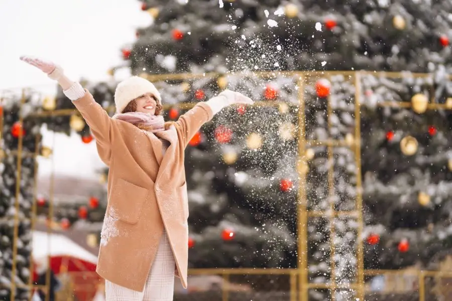 Woman playing in fake snow from snow machine at holiday event