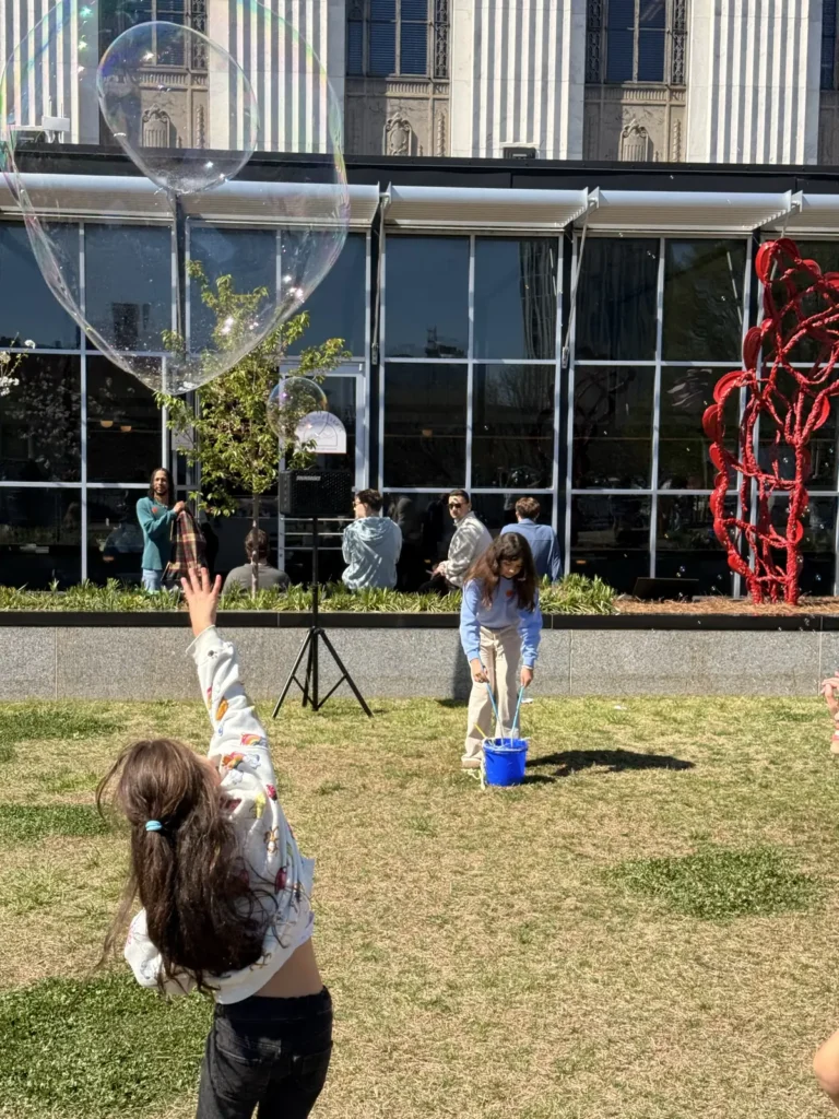 Girl reaching up to pop a giant floating bubble at a bubble party