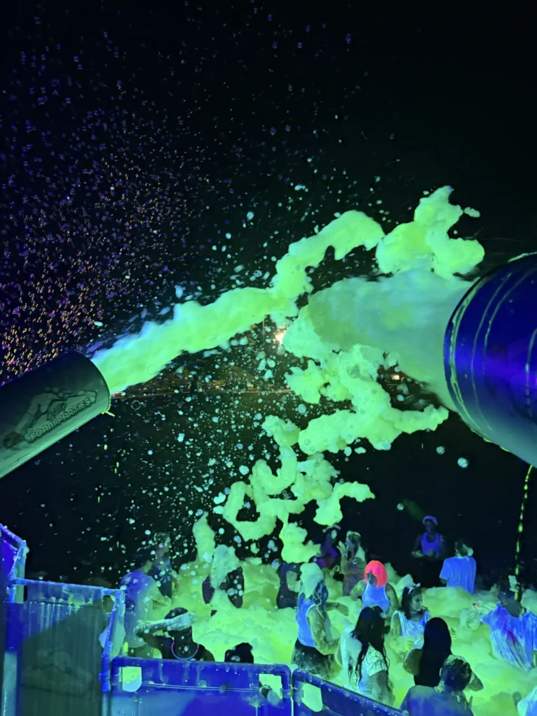 Foam cannon spraying glowing foam over a large crowd at night in Athens, Alabama