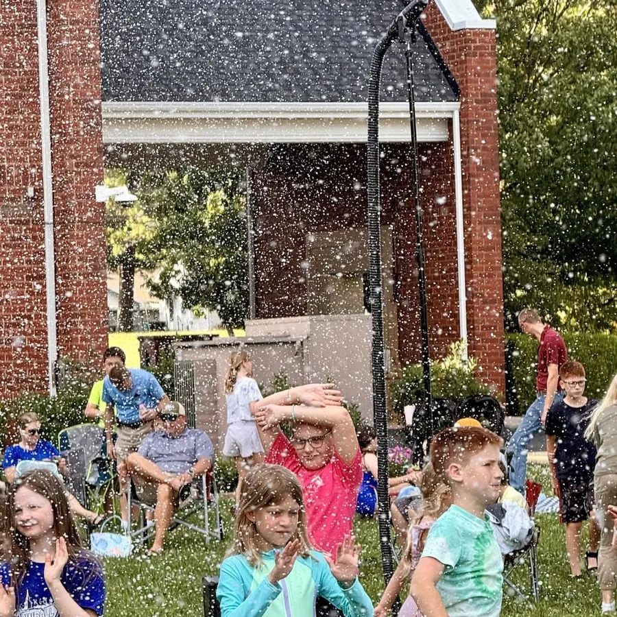 Kids enjoying falling snow at a summer church event