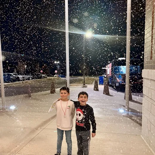 Kids standing in falling snow at a school event