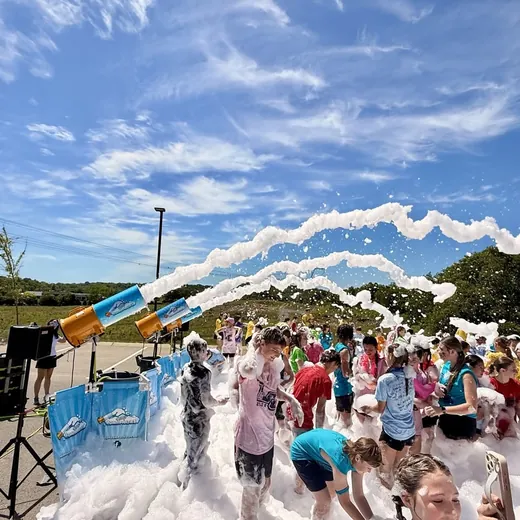 Students playing under foam cannons at a school foam party